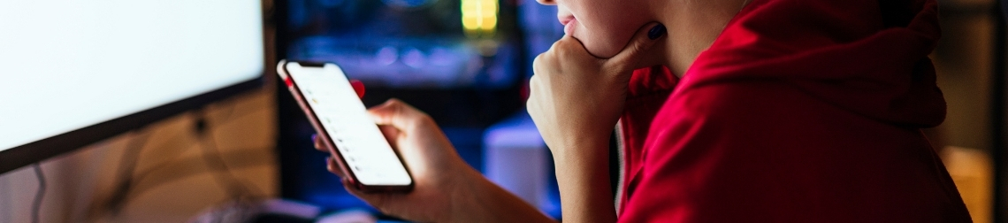 Person holding an iPhone and looking down at the screen.
