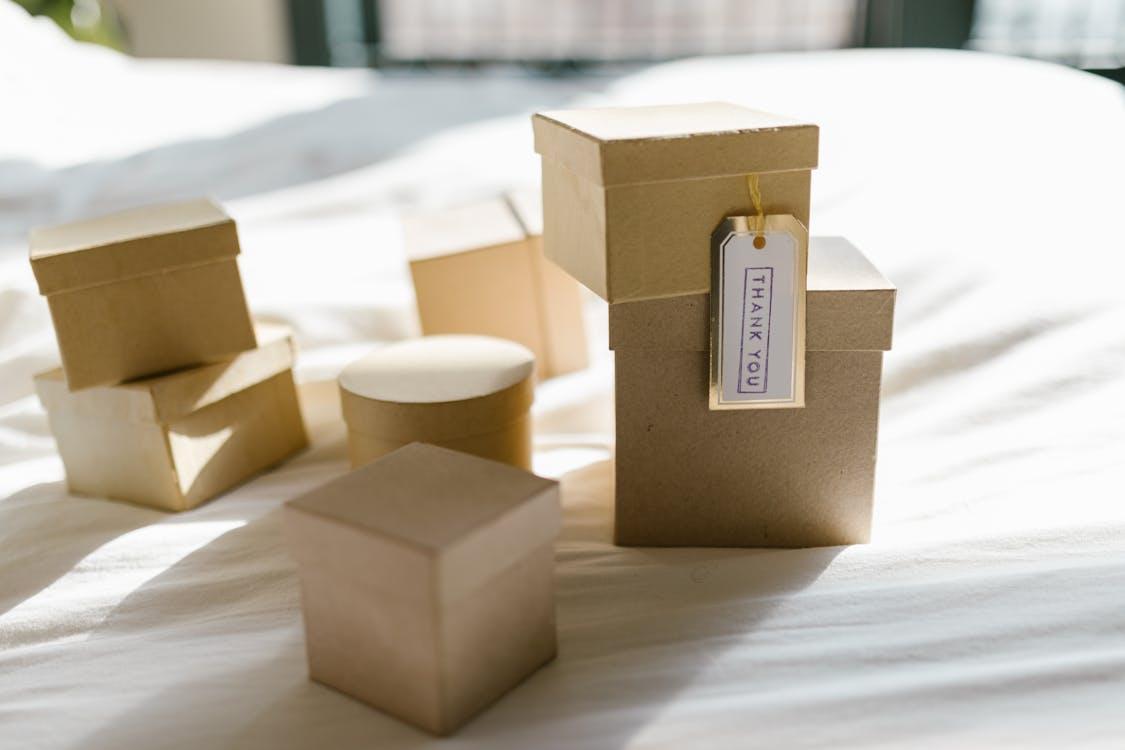 Free Cardboard gift boxes on a bed with thank you tag in natural light, perfect for product mockups. Stock Photo