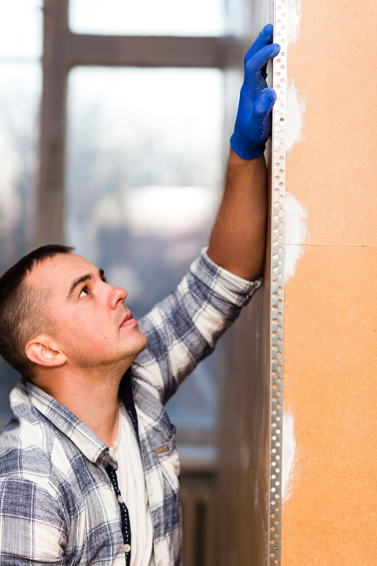 A carefully aligning and inspecting a garage door insulation on a drywall panel, ensuring proper positioning in a well-lit indoor environment