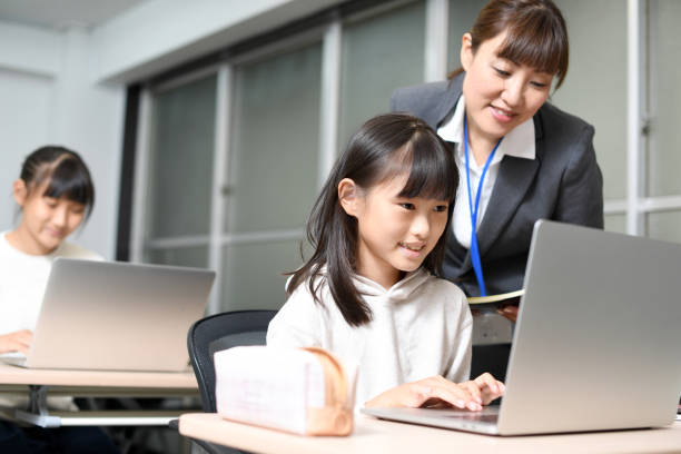 Several Asian elementary school girls are using laptops in the classroom and are being taught by a female teacher. Several Asian elementary school girls are using laptops in the classroom and are being taught by a female teacher. japan education tech stock pictures, royalty-free photos & images