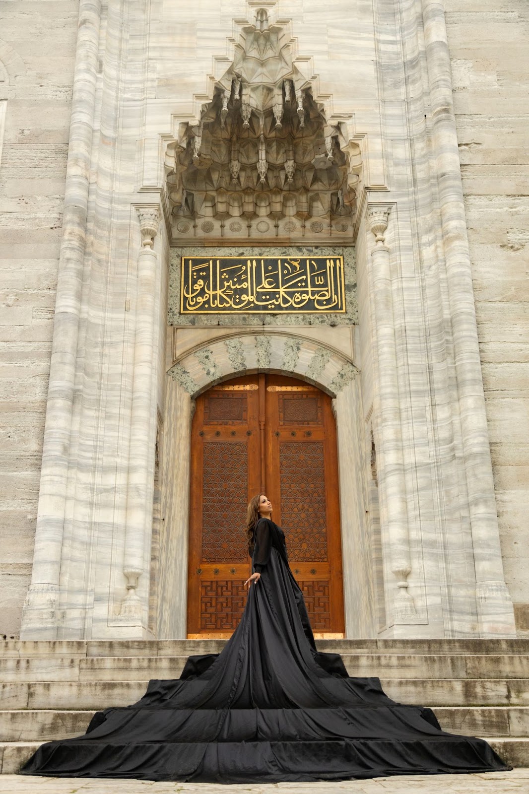 Sleek shoot at mosque entrance, black dress flowing.