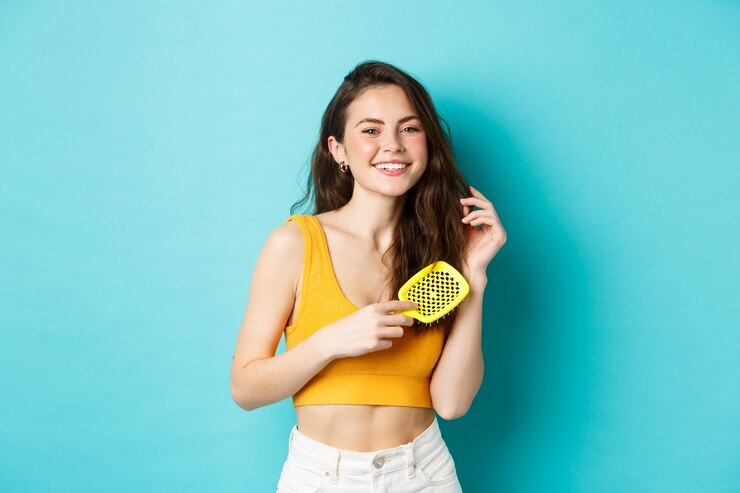 Woman smiling and combing hair with hairbrush