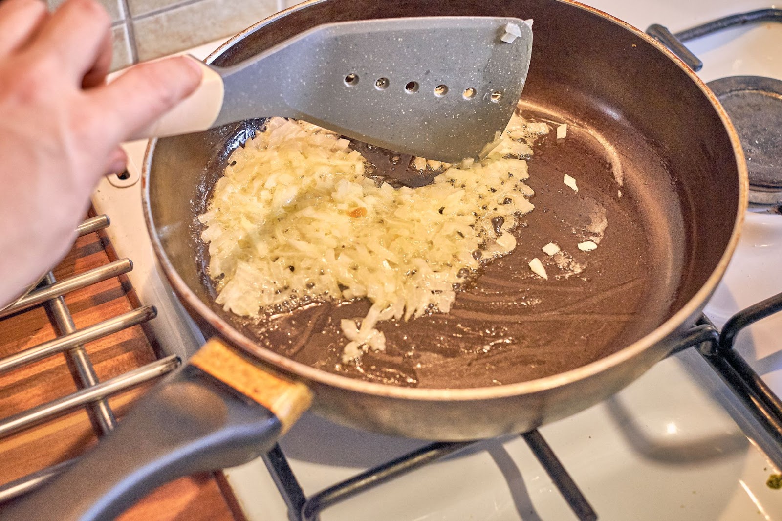 Chopped garlic being fried in a small amount of oil in a pan.

