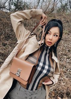 This contain an image of Jessi  posing with her handbag in the woods