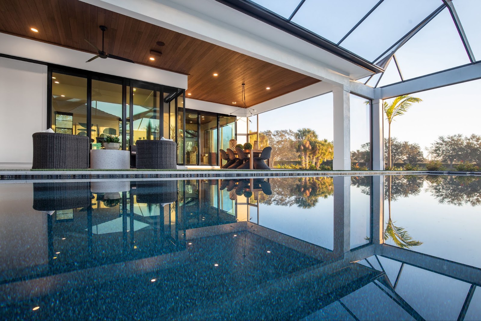 A home has a large pool and sliding glass doors with black trim.