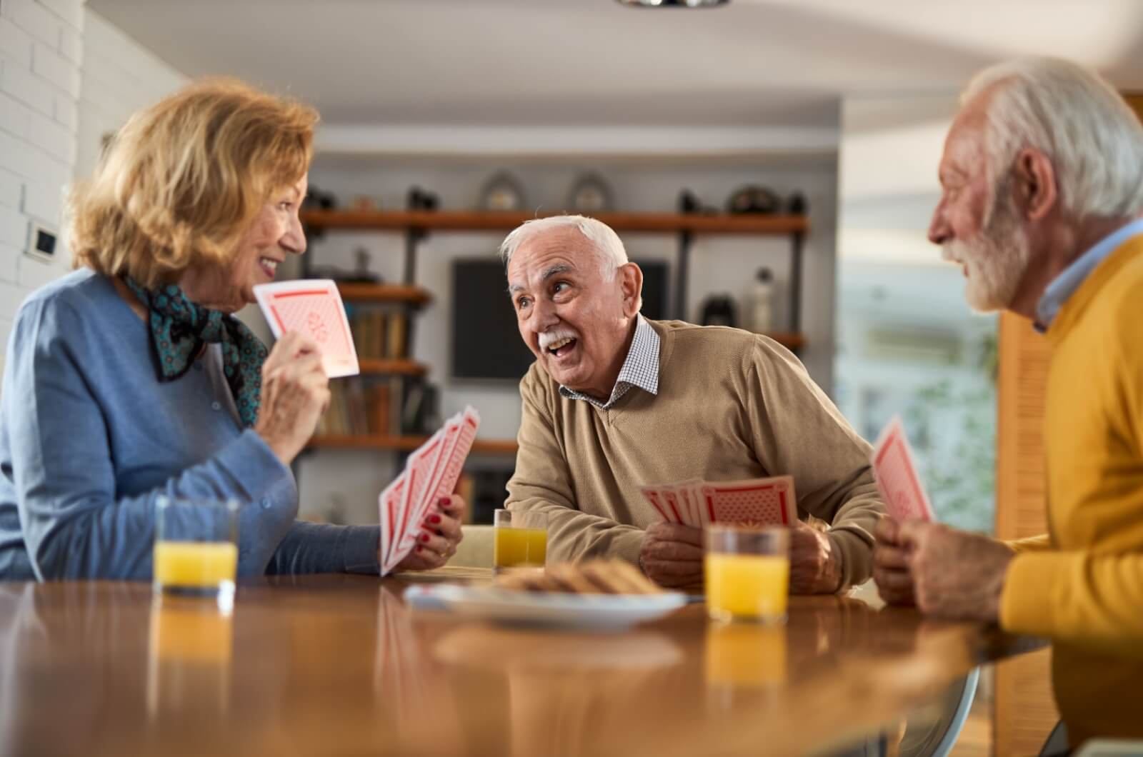 A group of happy older adults playing cards in senior living.