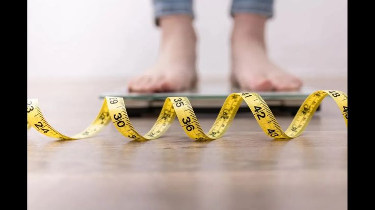 bmi calculator idea showcased with weight machine with a person feet and measuring tape