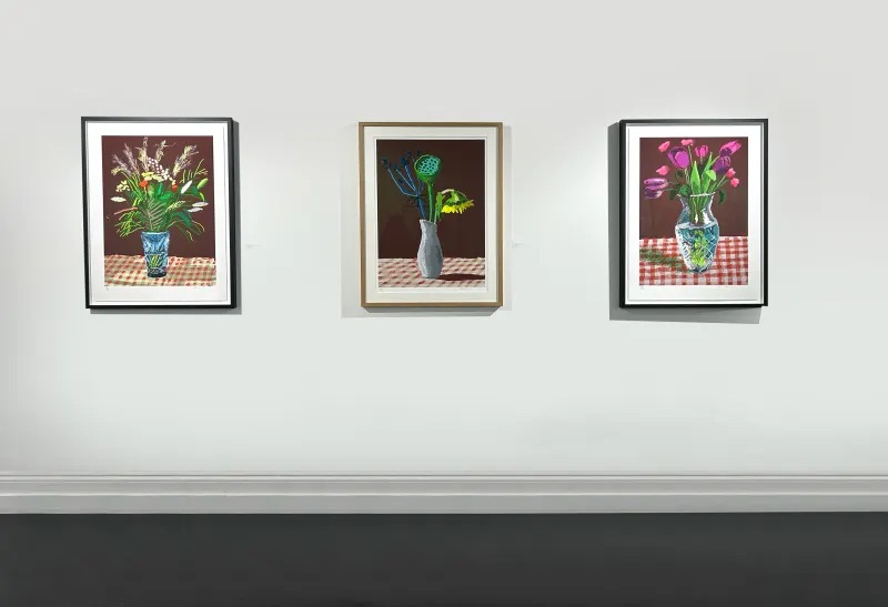 Three paintings from Hockney’s Flower series hang on a wall. David Hockney art prices hold strong in the current market.
