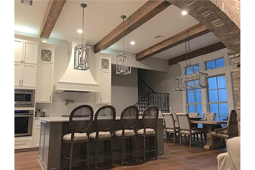 Eat-in kitchen with beamed ceiling, white cabinets, a rectangular dining set, and a center island with four seating.