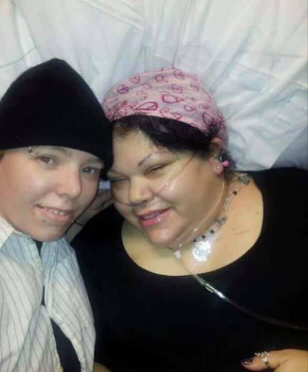 Wendy Lovedge and her wife smile for a picture while Wendi is hooked up to oxygen in the hospital.