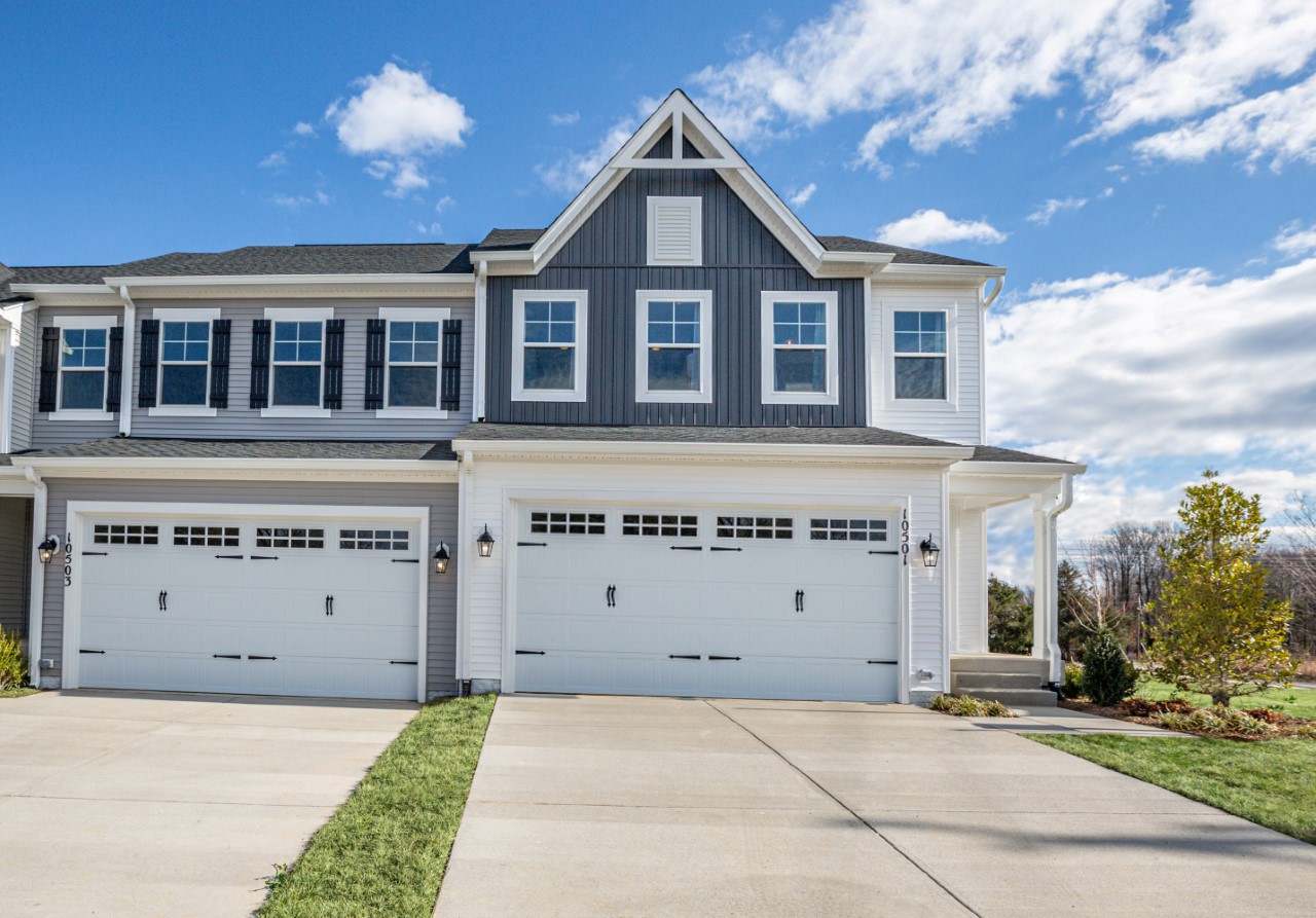 A newly built two-story townhome with a modern exterior, windows, and a garage