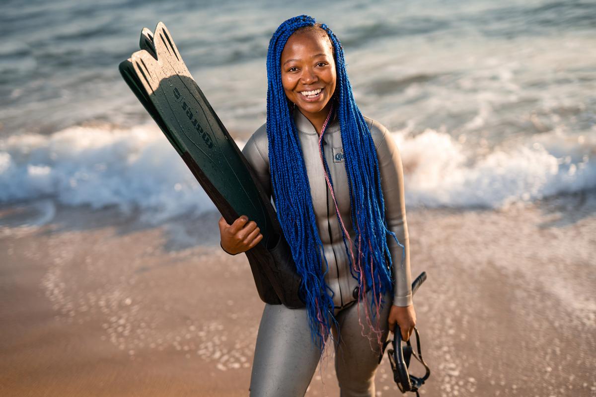 A photo of Zandile Ndhlovu smiling and wearing a diving suit.  