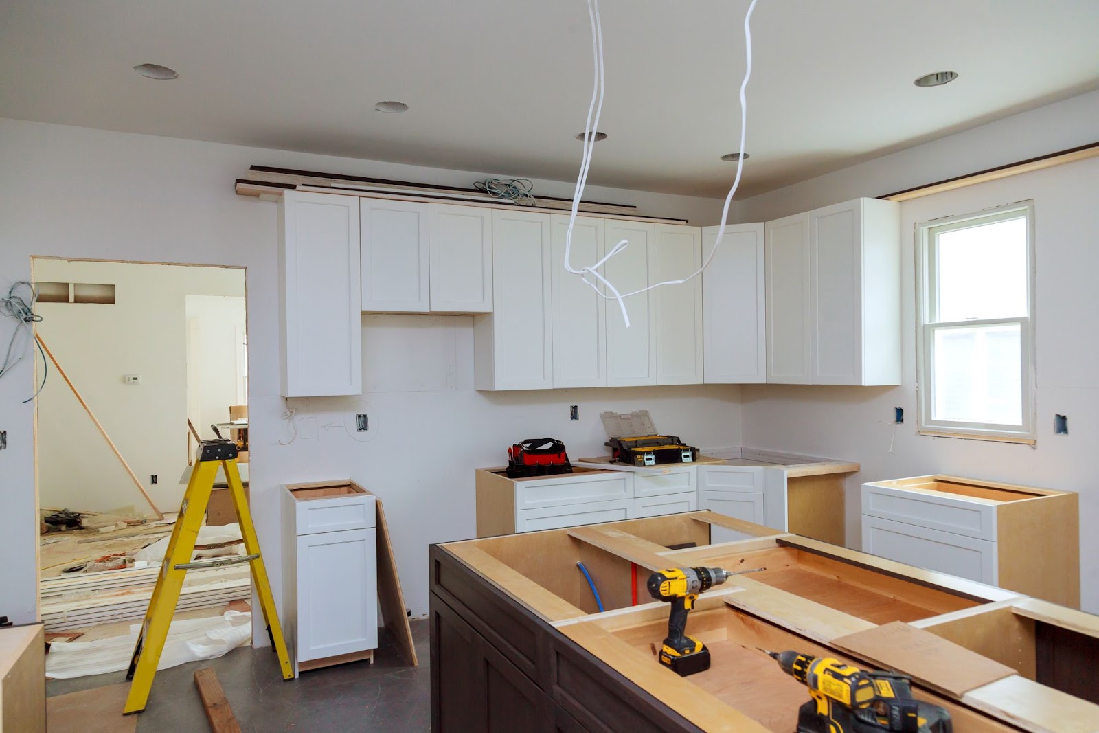  White wooden cabinets installed during kitchen remodeling on a partially completed furniture set.