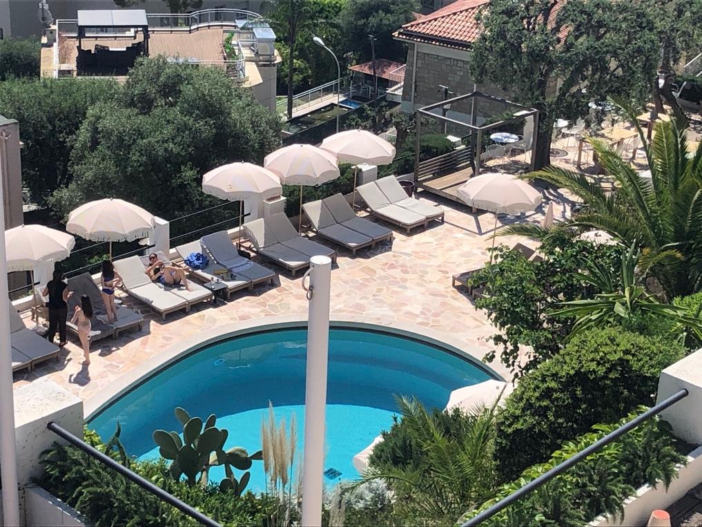 A pool with umbrellas and chairs

Description automatically generated