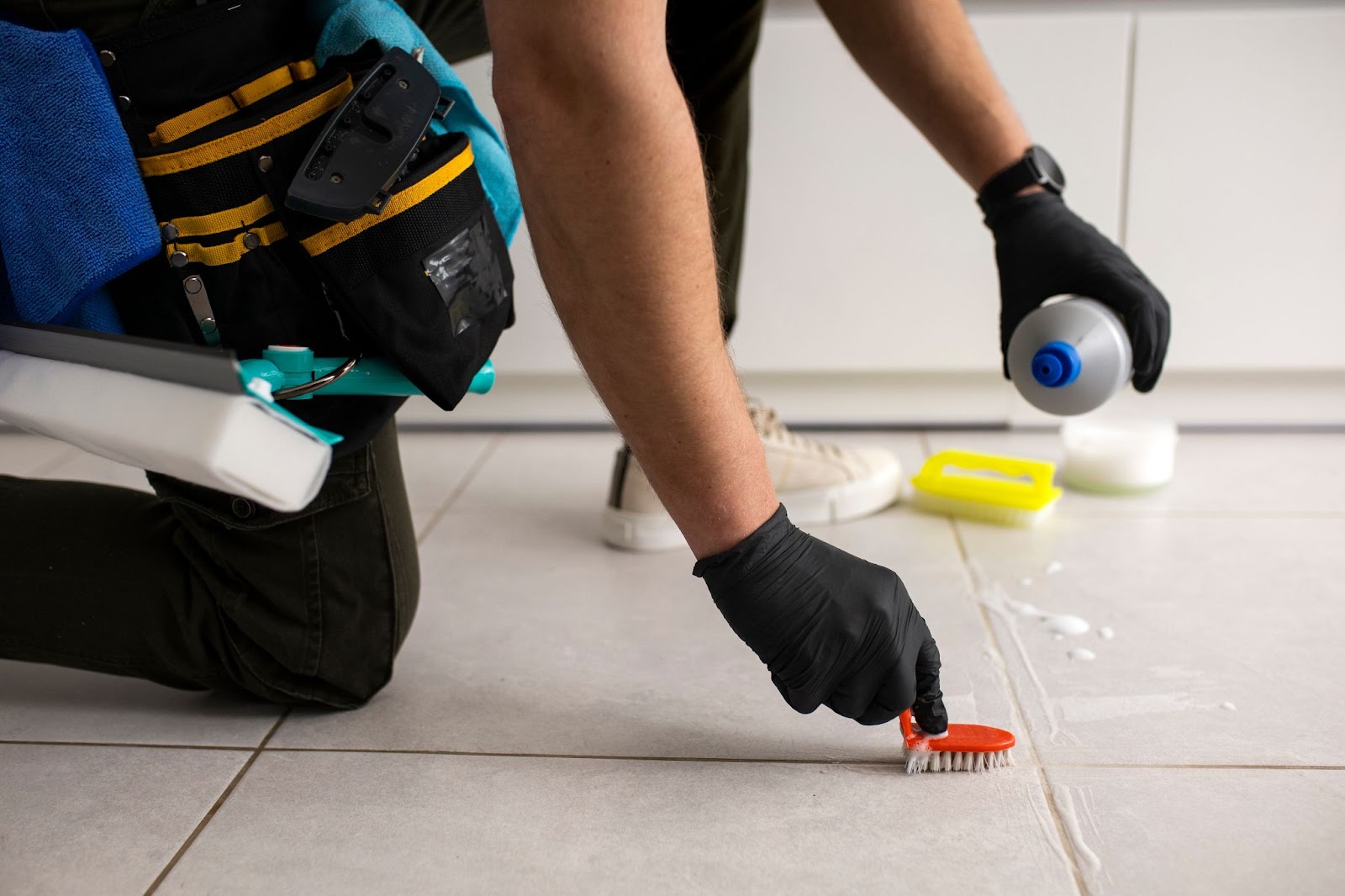 Person cleaning the floor with bottle of liquid and a small brush_Preferred Construction