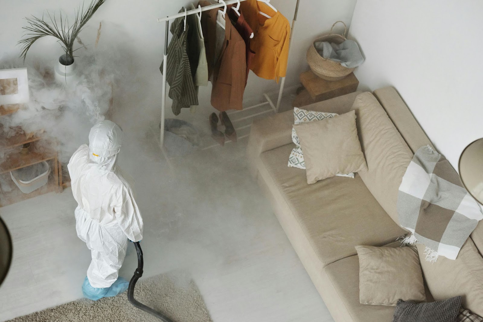 Indoor pest control fogging in a residential living space, performed by a technician in safety gear.