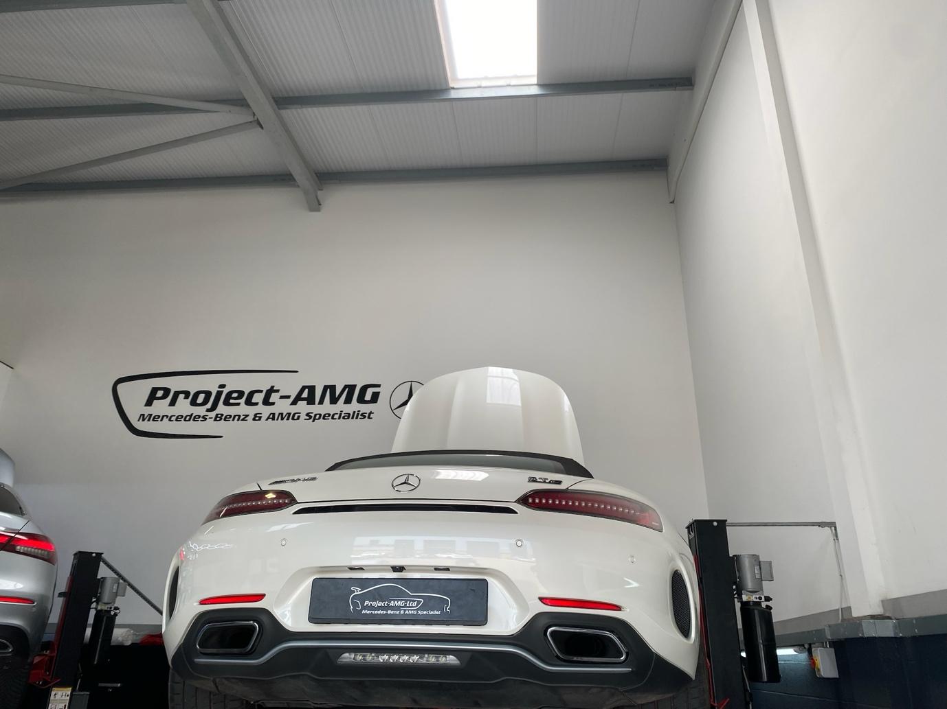 Rear view of a white Mercedes-AMG sports car on a lift at Project-AMG garage, a Mercedes-Benz & AMG specialist