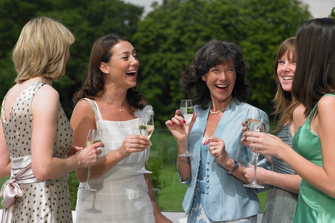 Bride laughing joyfully with well-dressed wedding guests at a wedding.