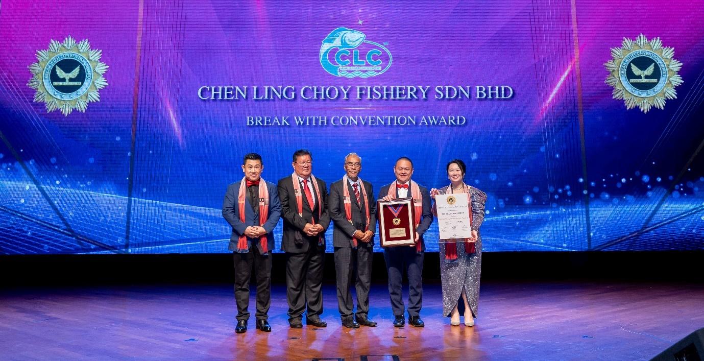 A group of men standing on a stage holding a plaque

Description automatically generated