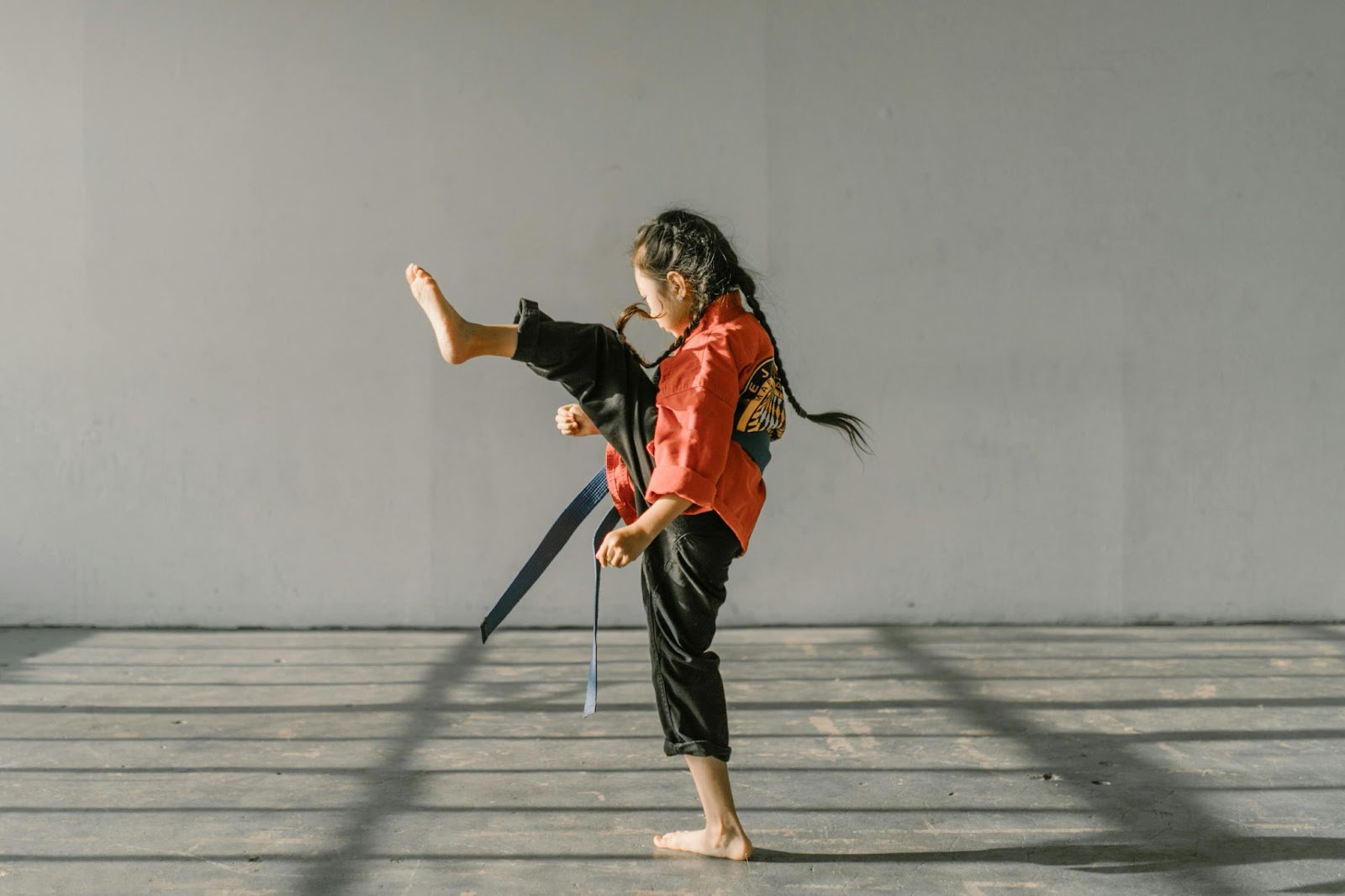 A young martial arts student in the middle of a kick with one leg raised high