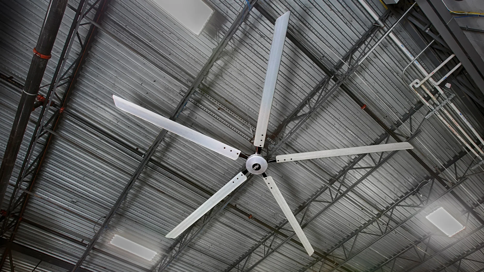 A large HVLS fan suspended from a warehouse ceiling.