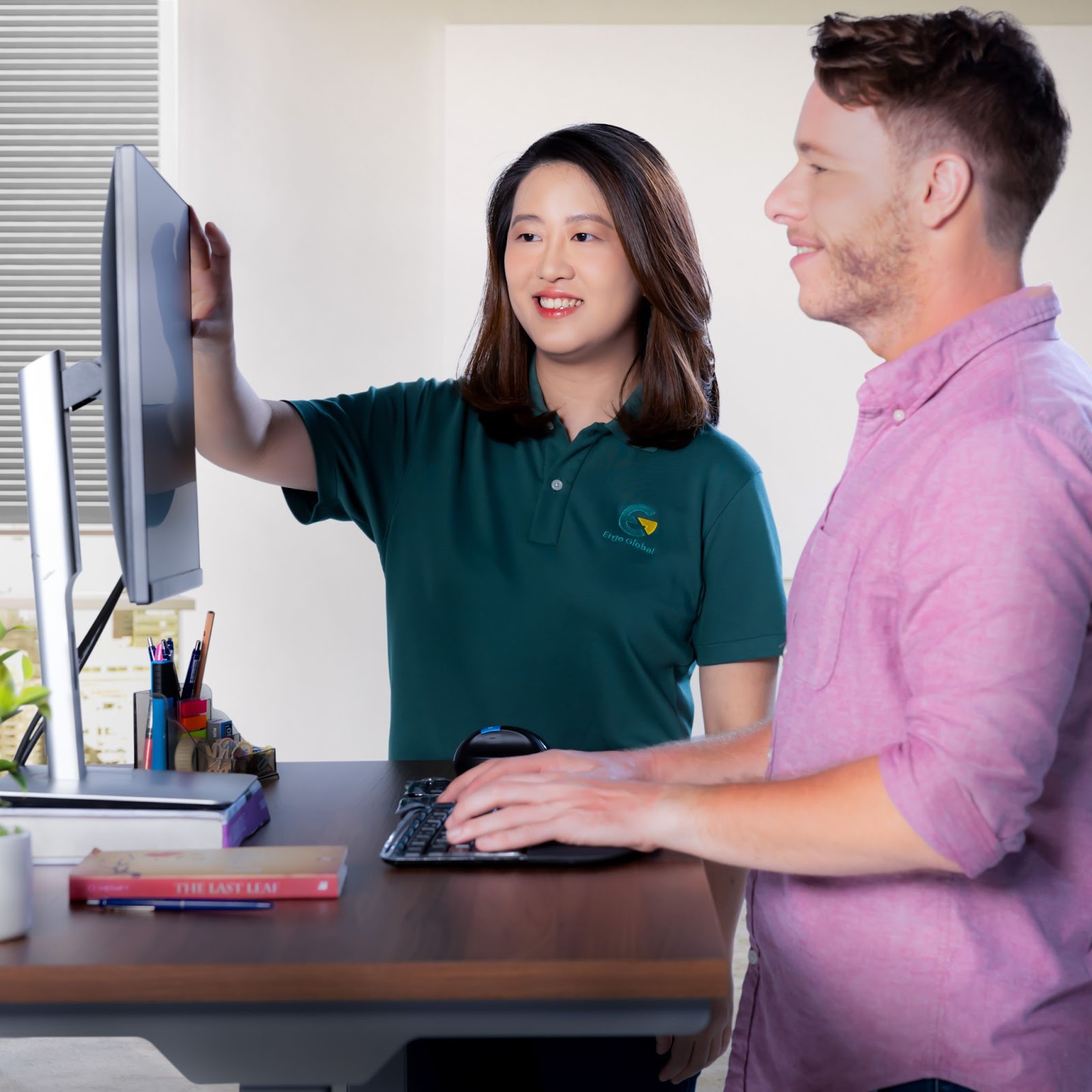 An certified ergonomics consultant offering an explanation of monitor height to a worker