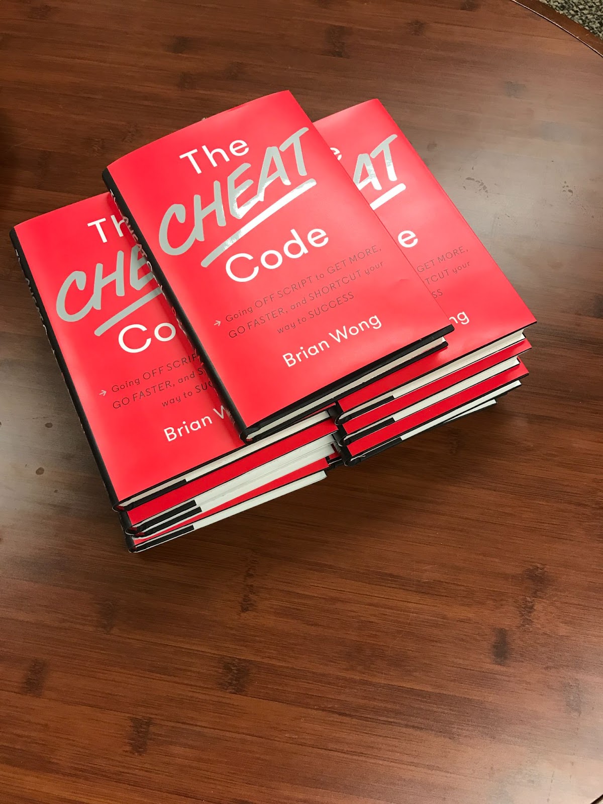 A stack of copies of the book The Cheat Code 