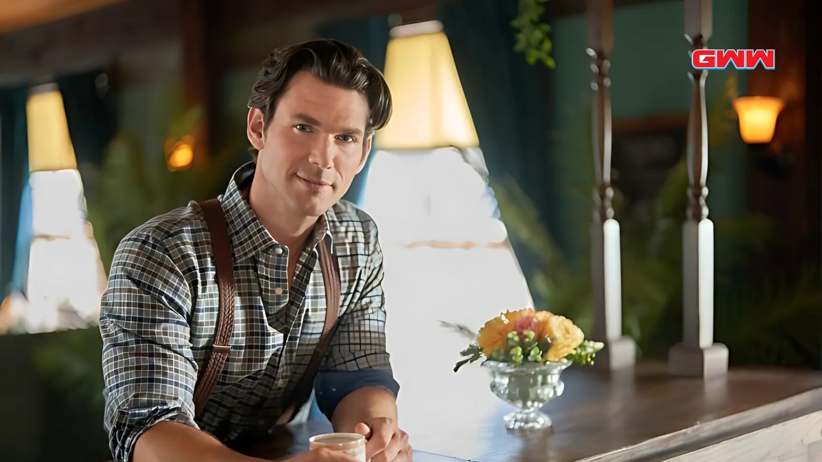 Nathan Grant sitting at a bar, holding a cup, and smiling.