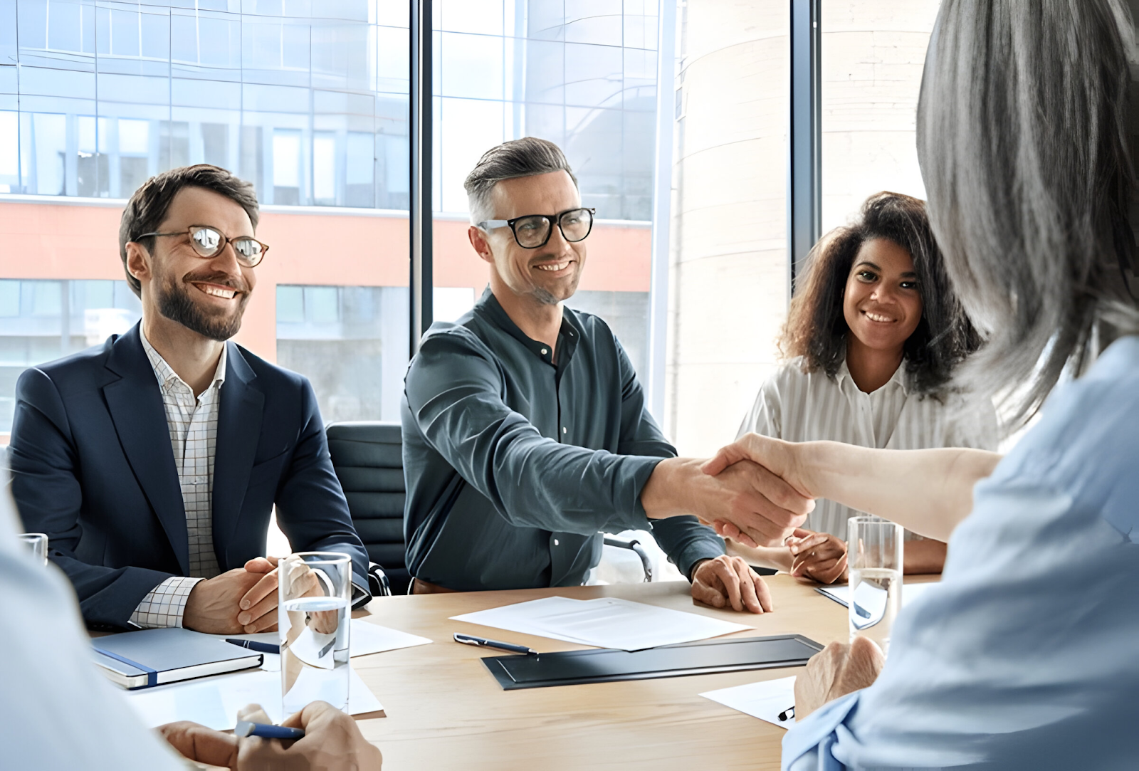 Business professionals shaking hands during a successful merger and acquisition meeting, symbolizing agreement and collaboration.