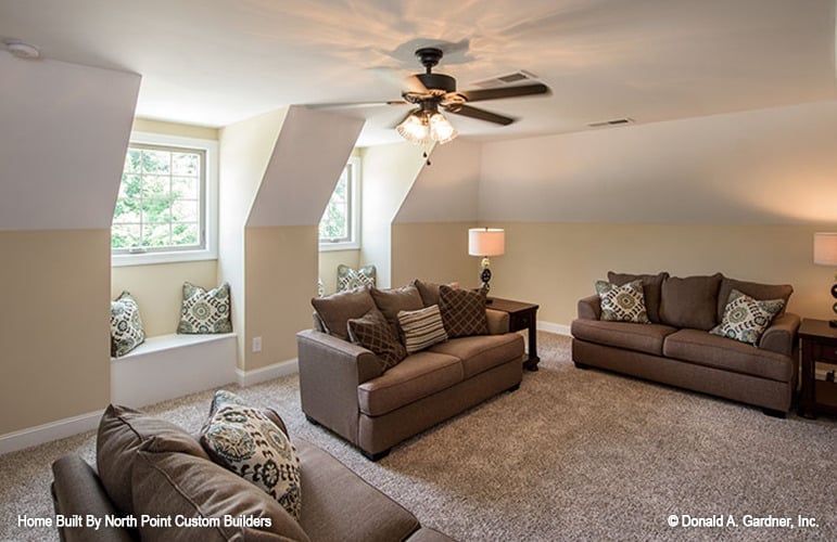 Bonus room with carpet flooring, window seats, and brown sofas.