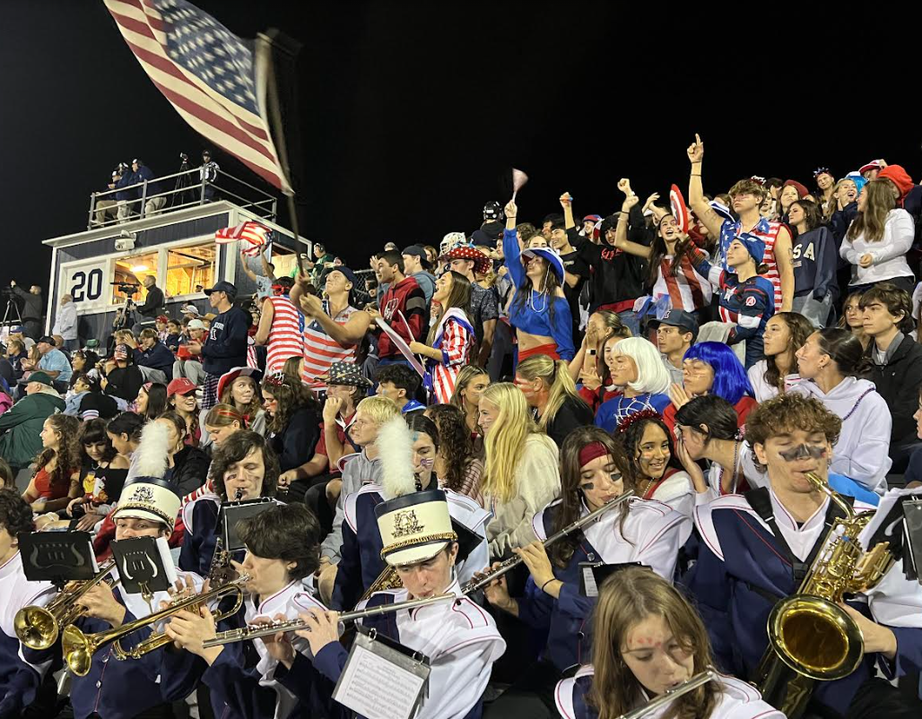 image of students cheering on the football team and the band