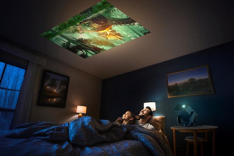 A person and person lying on a bed with a projector above them

Description automatically generated