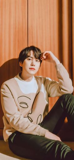 This contain Kyuhyun sitting on the floor with his hands behind his head, wearing a sweatshirt and pants