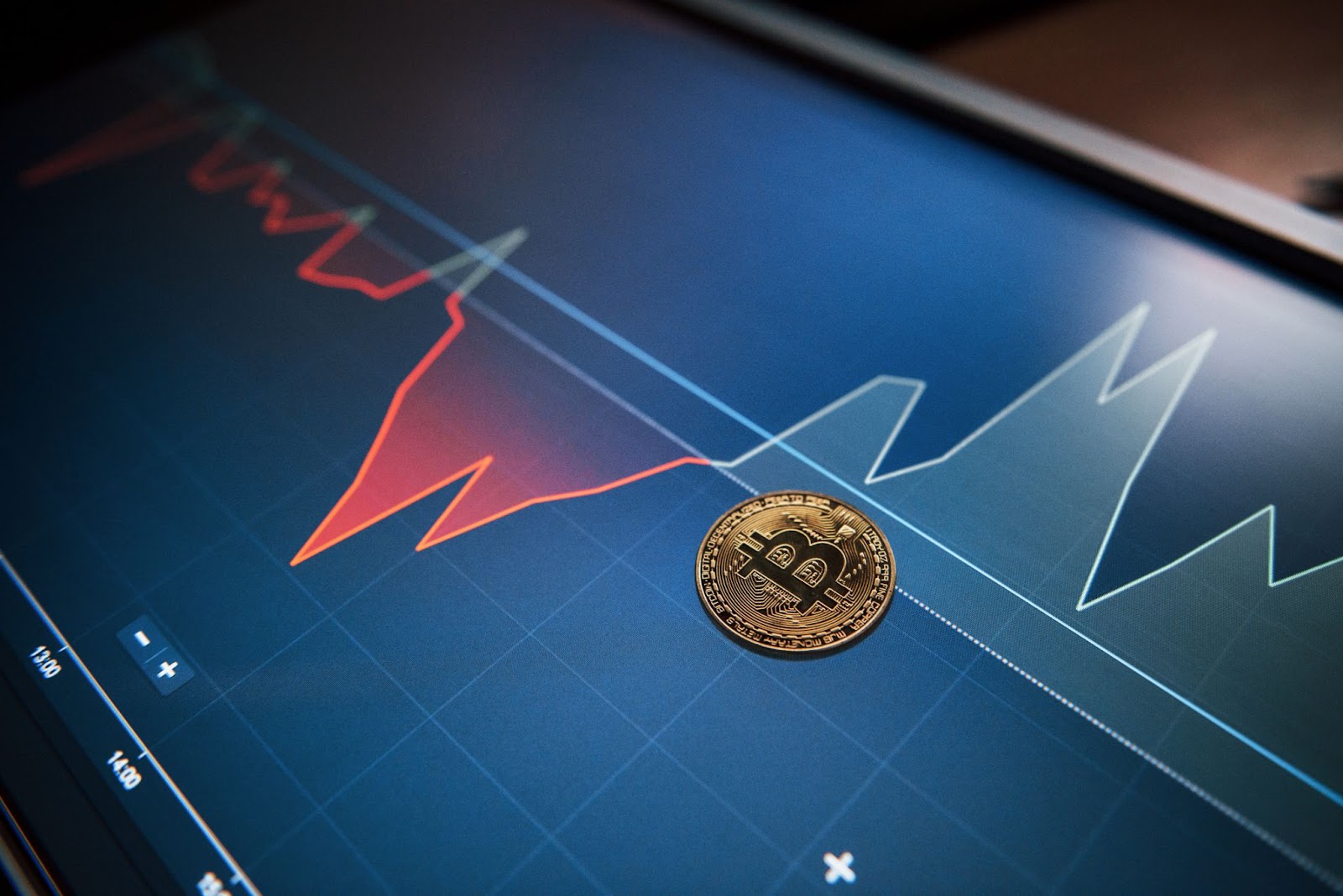  Picture of golden bitcoin lying on the display with graphs in office