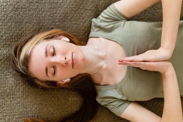 Woman with her eyes closed, meditating peacefully on her back

