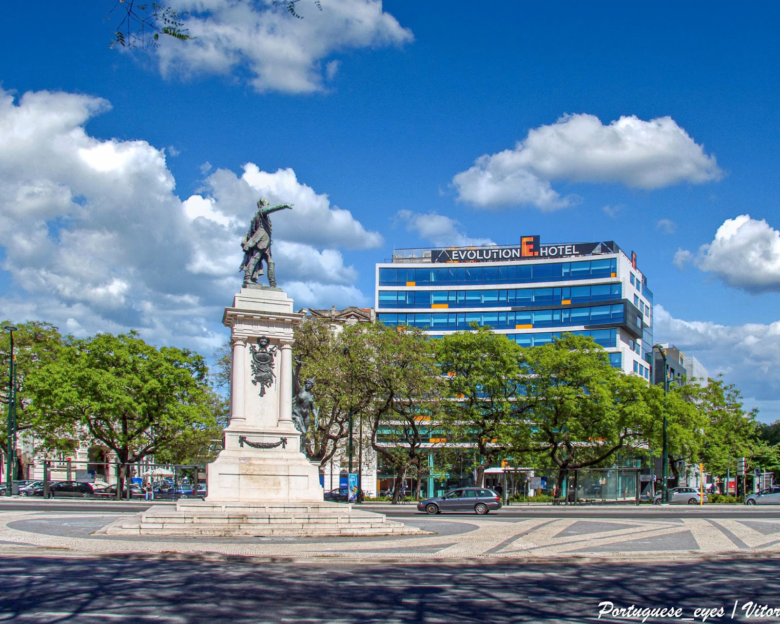 Statue with green trees and a blue sky.