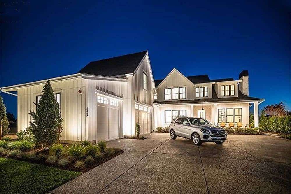 This lovely Farmhouse-style two-story home has brilliant exterior walls complemented by the warm lights of the windows matched by the exterior lights and the surrounding landscaping with a simple beautiful vibe to it.