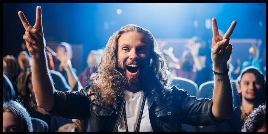 A person with long hair and beard in a black jacket with a blue light behind him

Description automatically generated