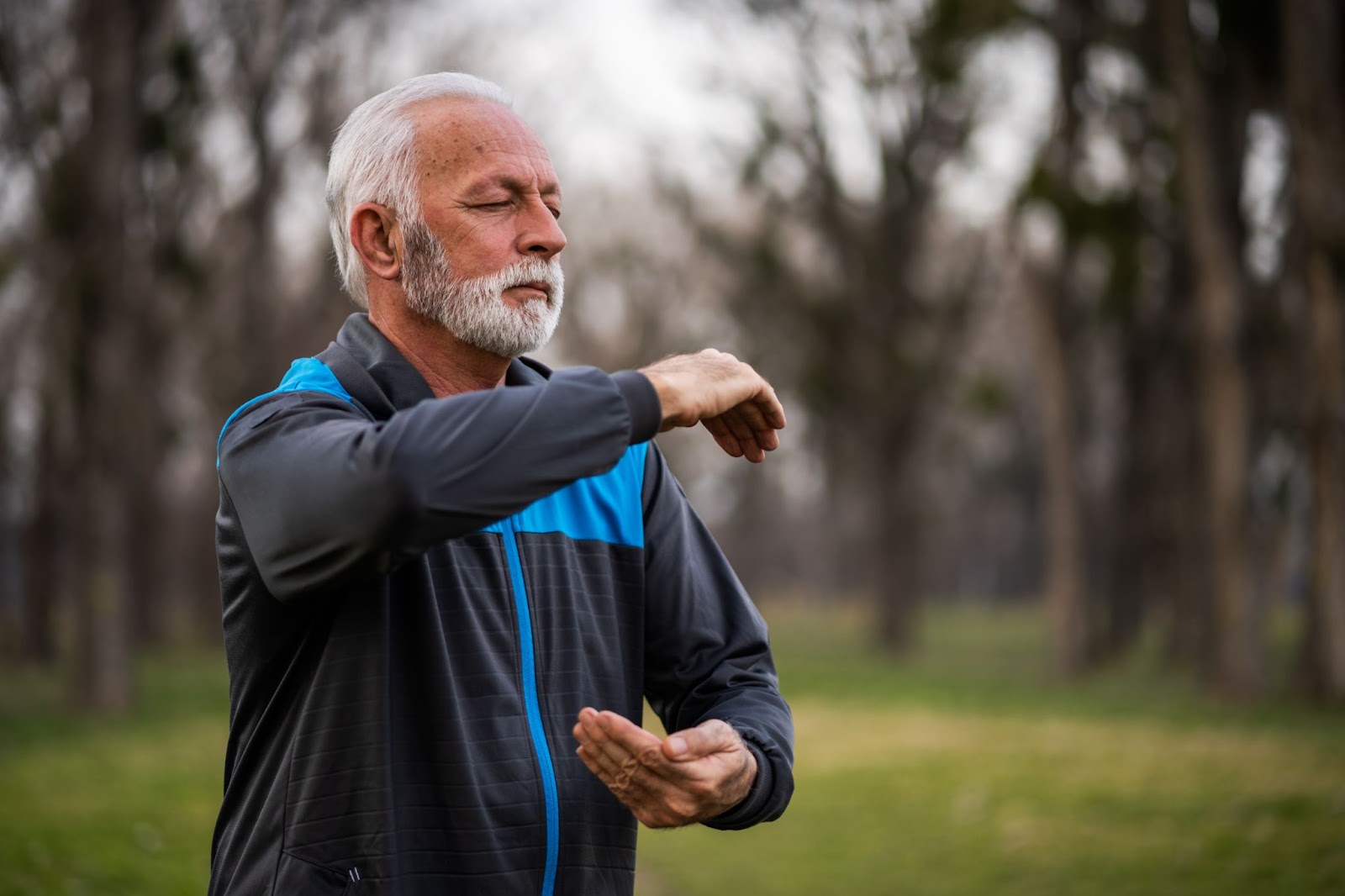 Homem sênior grisalho praticando Tai Chi de olhos fechados