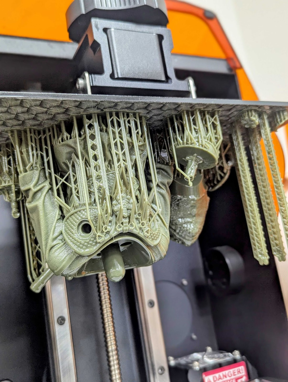 Close-up of a resin 3D printer build plate with a highly detailed model and dense tree-like support structures still attached, post-printing.
