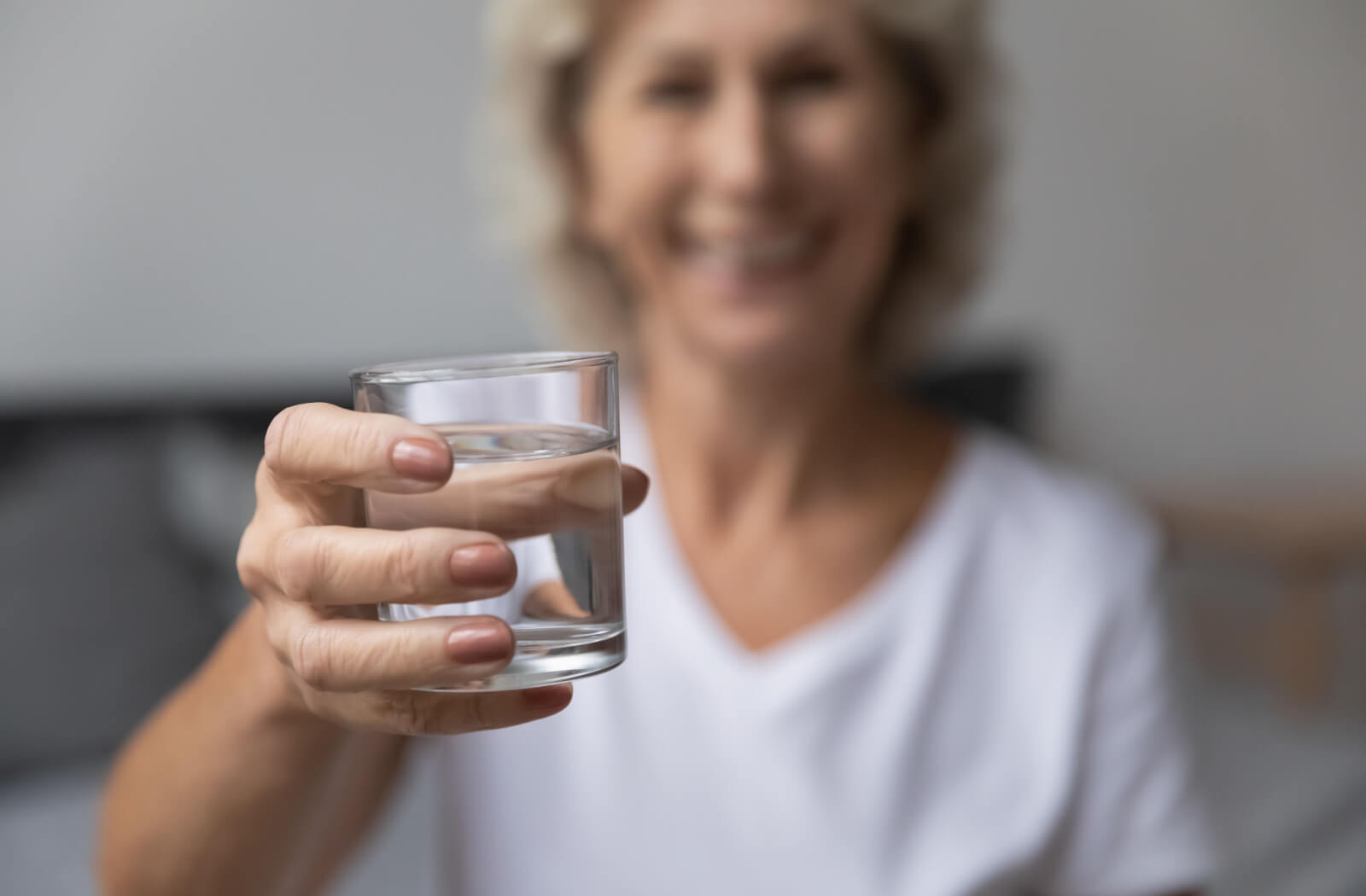 A focused image of an older adult with dementia raising a glass of water to stay hydrated.