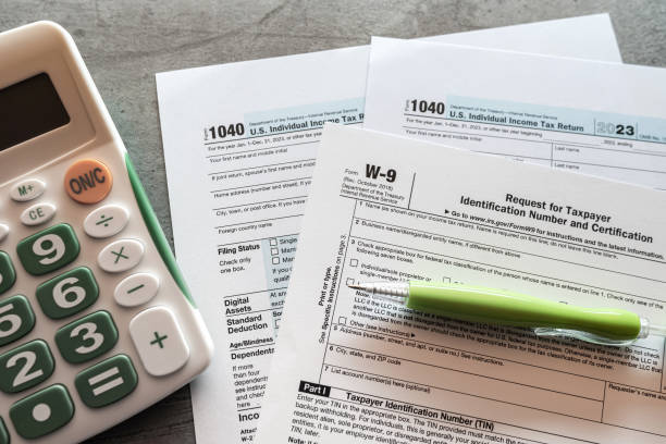 1040 US tax form with pen and calculator on office desk federal tax refund, federal government 1040 US tax form with pen and calculator on office desk. Taxes burden IRS Tax Form stock pictures, royalty-free photos & images