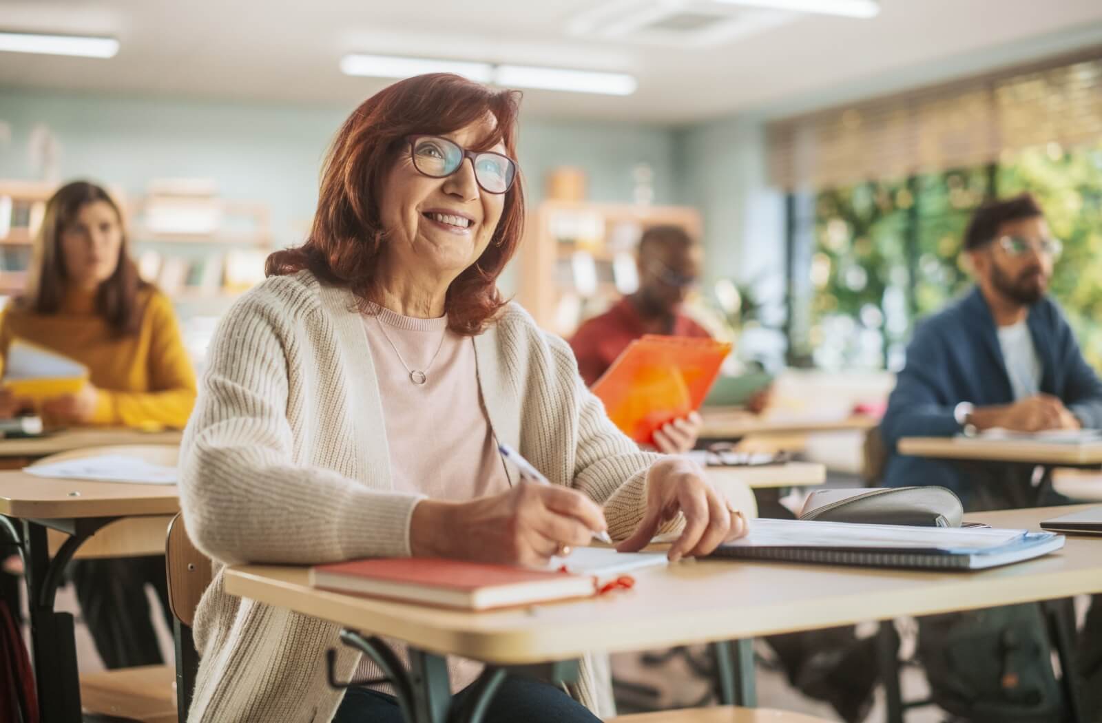 A smiling senior unbothered by aging sits in a class to learn a new skill.