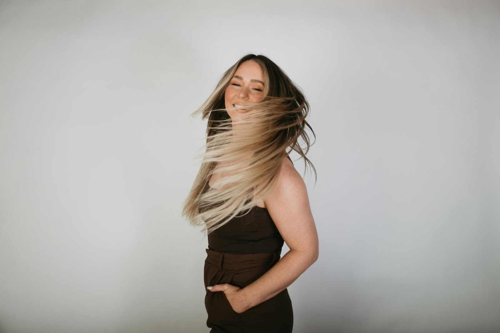 A smiling woman flipping her ombre hair, demonstrating the movement and lightweight feel of micro link extensions.