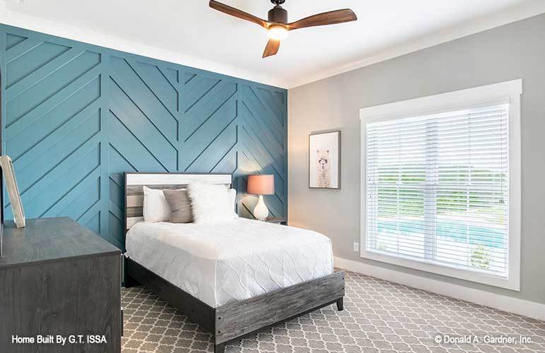 A blue chevron accent wall sets a nice backdrop to the dark wood bed of this bedroom.