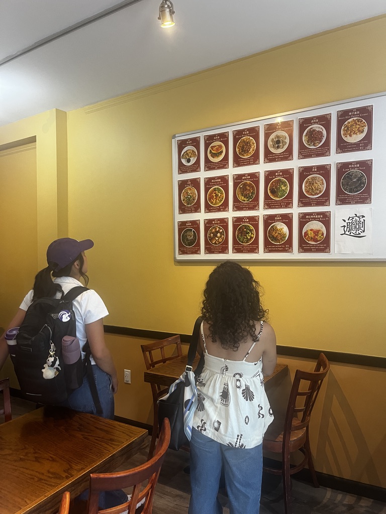 Two people read the menu on the wall in Lili's. 