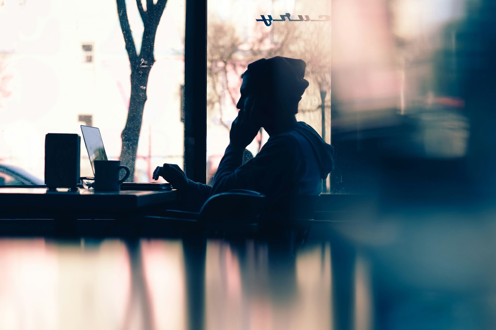 Man in a beanie working on a laptop in a cafe