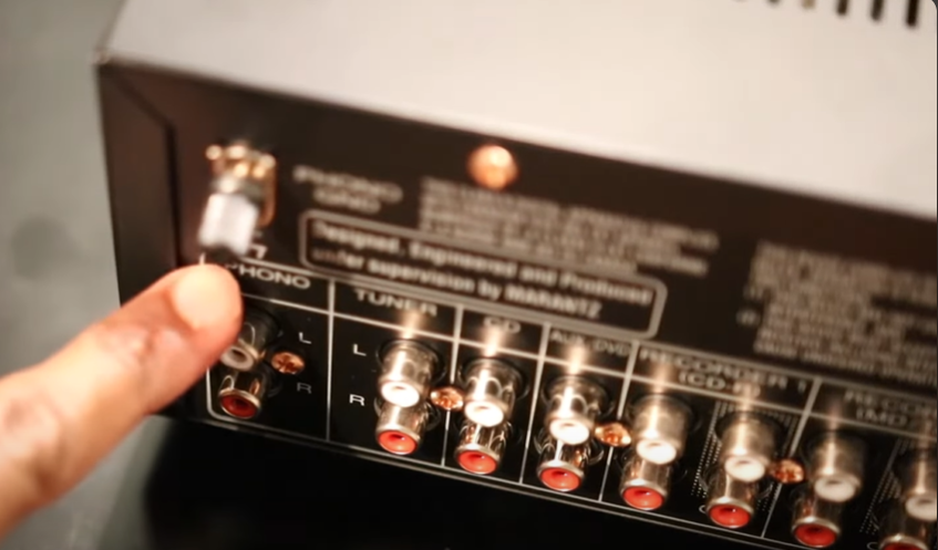 Person pointing to the phono input on the back of a Marantz audio receiver.