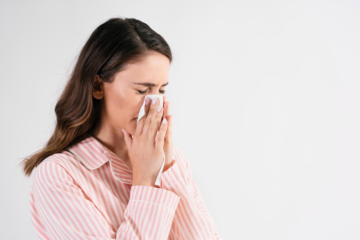 A person blowing her nose

Description automatically generated