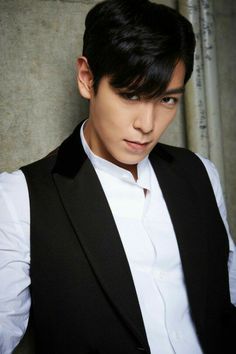 This contains an image of BIGBANG's T.O.P wearing a black vest and white shirt